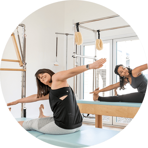 fit women stretching during a duet pilates session in a boutique studio